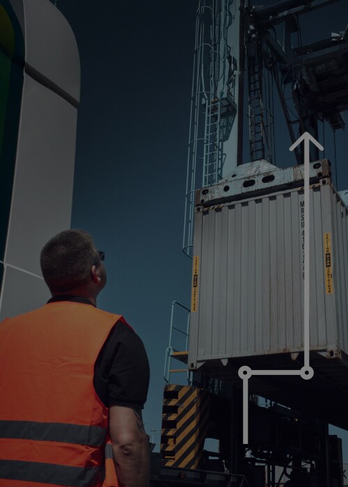 Worker watching container lifted by crane