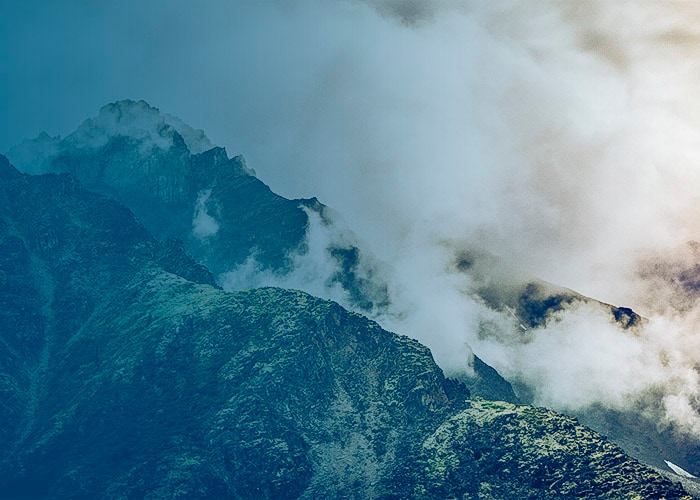 Misty mountain ridge with rocky peaks partially covered in clouds and fog